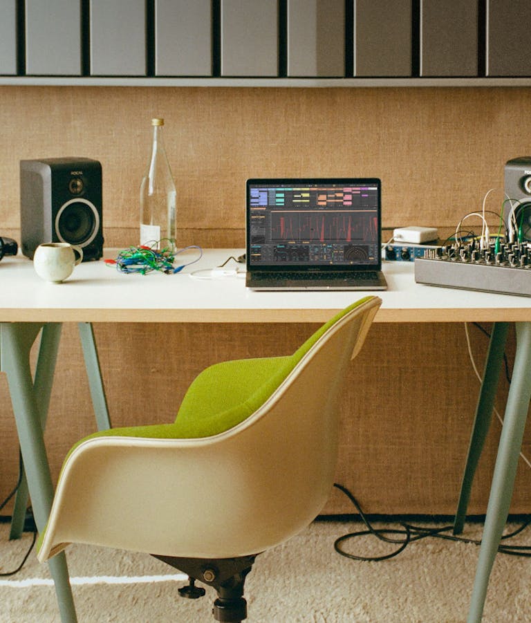 A music studio is shown, Ableton Live is being used in the background
